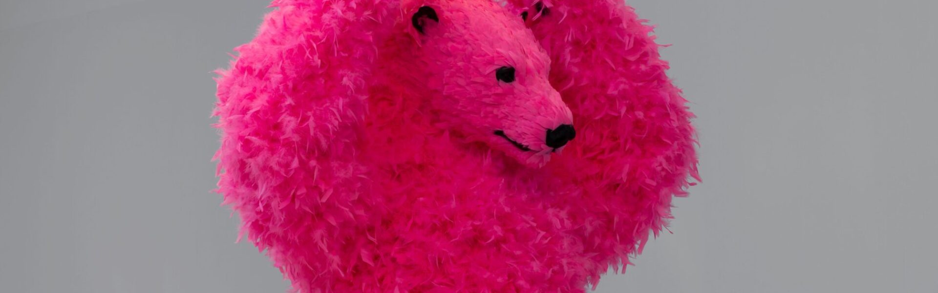 A sculpture of a dancing pink polar bear with feathers instead of fur.