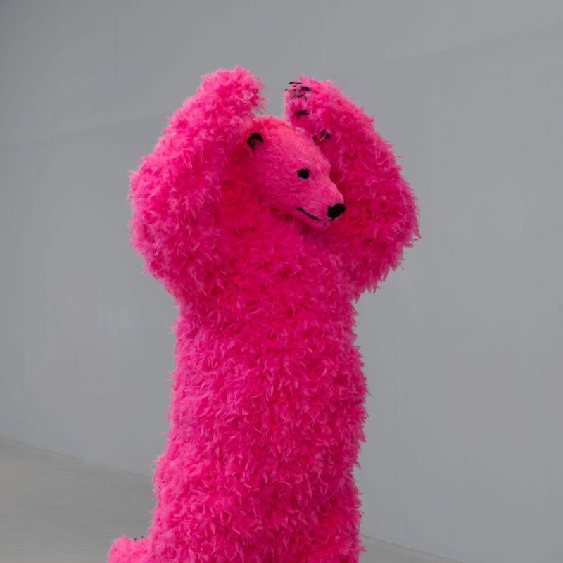 A sculpture of a dancing pink polar bear with feathers instead of fur.