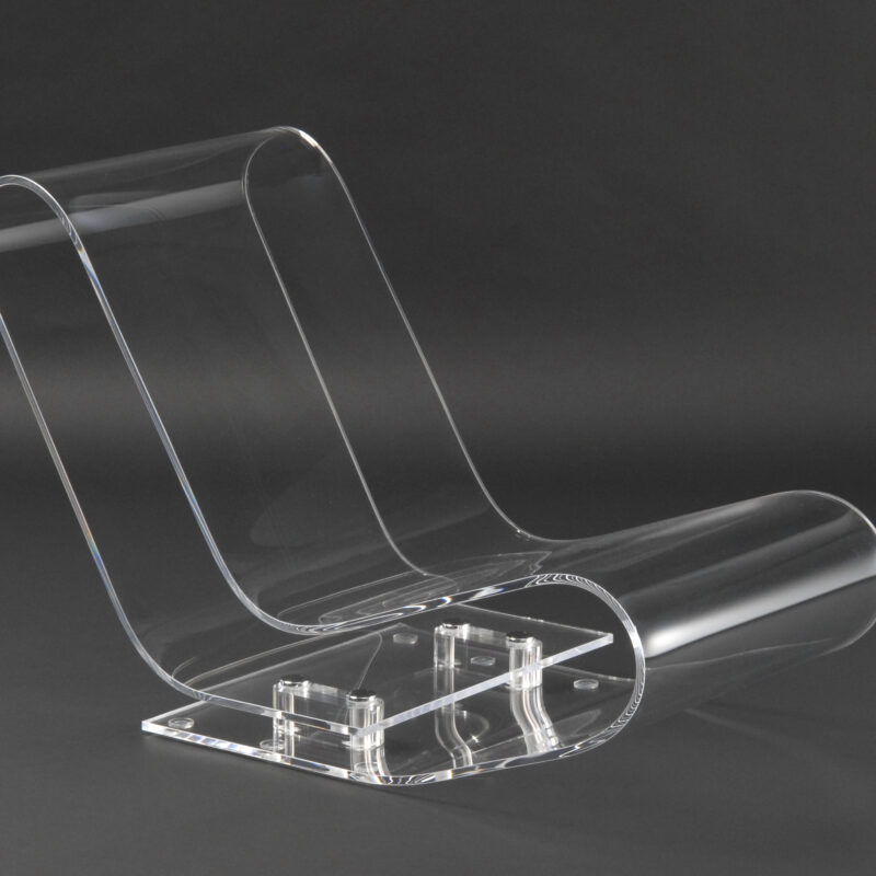Transparenter, geschwungener Stuhl aus Acryl mit flacher Sitzfläche und Rückenlehne, auf rechteckiger Basis mit Befestigungselementen.