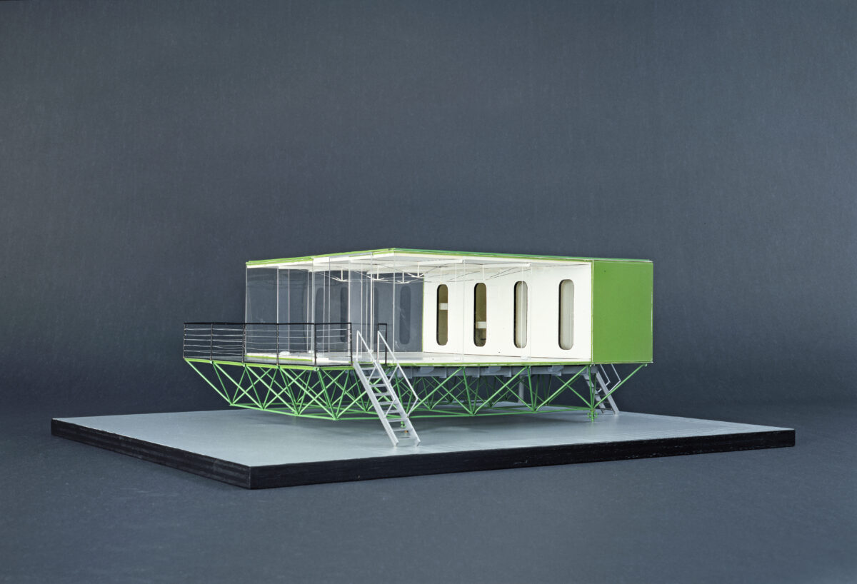 Modell eines modernen Wohnhauses auf grünem Fachwerkgestell mit rechteckigem Grundriss, weißen Wänden und großen Fenstern.