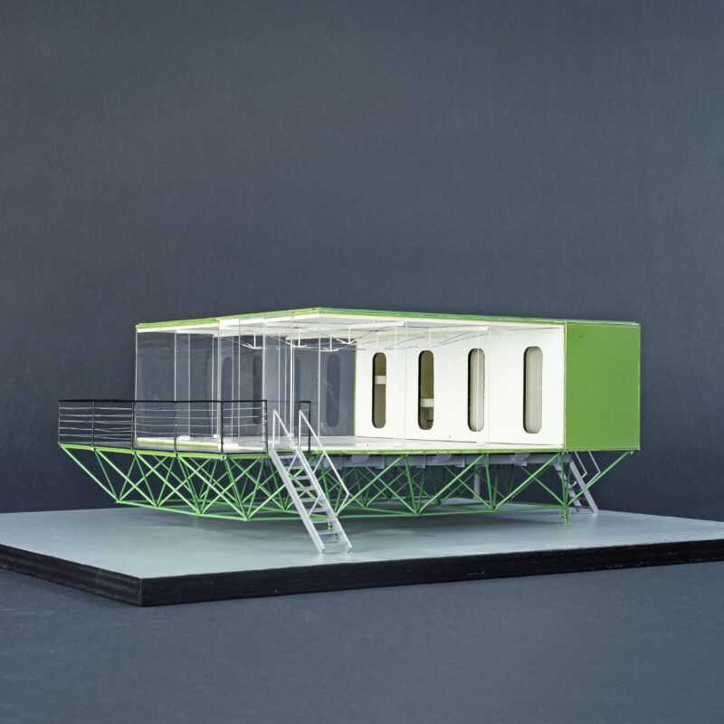 Modell eines modernen Wohnhauses auf grünem Fachwerkgestell mit rechteckigem Grundriss, weißen Wänden und großen Fenstern.