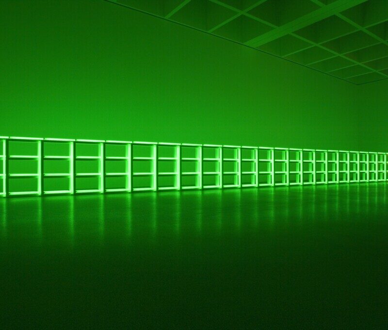 Ein leuchtend grünes Raster, das sich horizontal an der Wand eines dunklen Raums entlangzieht.