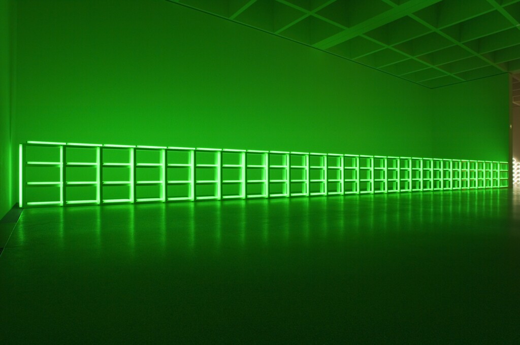 Ein leuchtend grünes Raster, das sich horizontal an der Wand eines dunklen Raums entlangzieht.