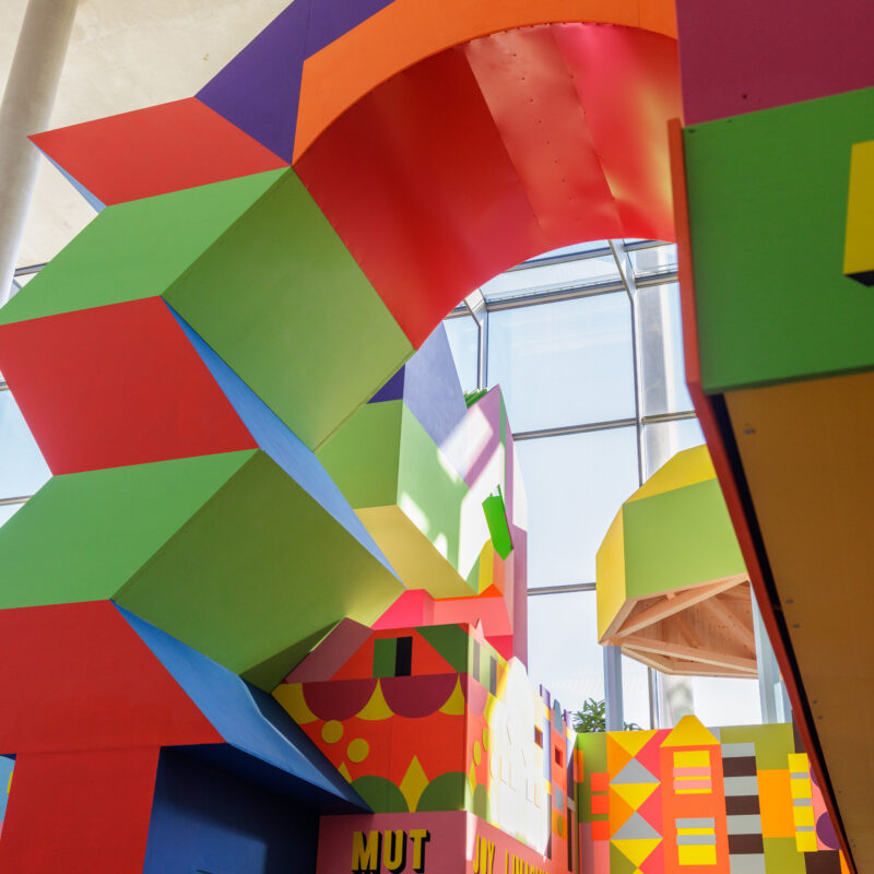 Bunte, geometrisch geformte Architektur mit großen Bögen und Fenstern in einem Innenraum