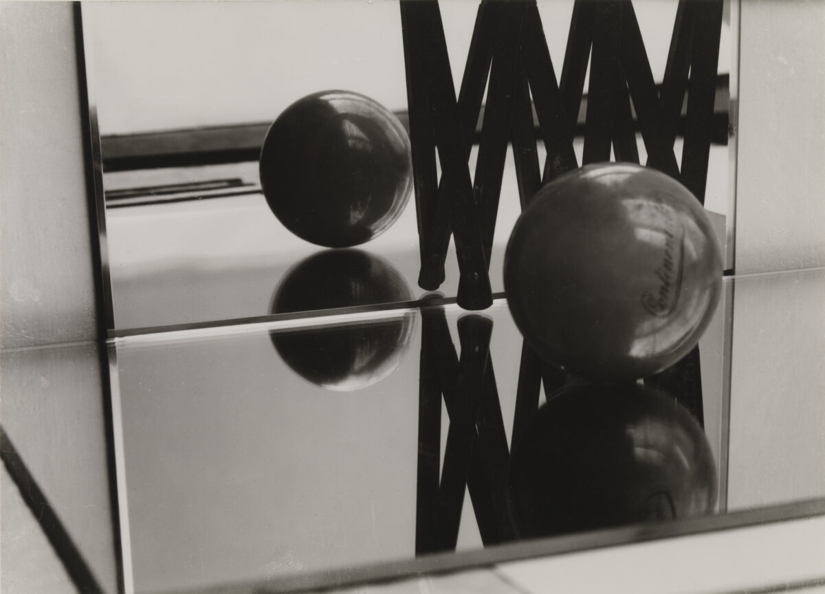 Ein Ball liegt auf spiegelnden Flächen vor mehreren Spiegeln, die sein Spiegelbild mehrfach zeigen.